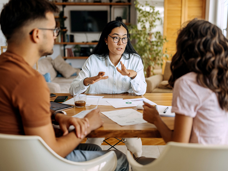 Jeune couple assis à une table, recevant les conseils d'un expert financier