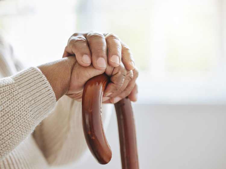 Des mains d'une personne d'un certain âge, posées sur une canne