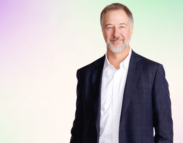 David Picton debout avec un arrière-plan coloré derrière lui.