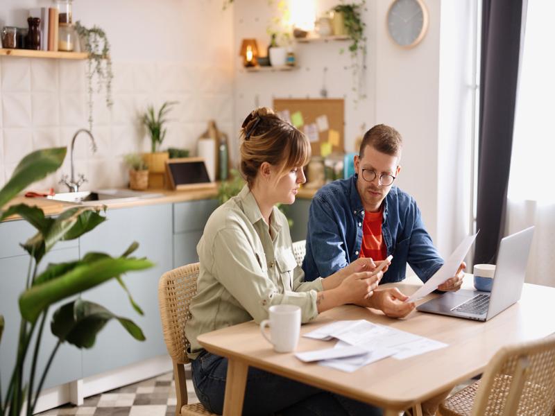 Un couple assis à la table de la cuisine en pleine discussion sur les finances.