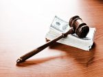 Marteau de juge sur un socle à côté de pièces empilées et de billets de banque.