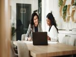 Deux professionnelles échangeant autour d’un ordinateur portable, illustrant le conseil financier personnalisé et la relation client.