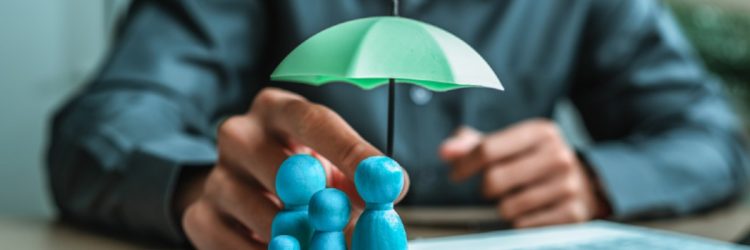 Une poupée en bois sous un parapluie tenue par l’agent représentent l’assurance. La famille, la protection, la vie.