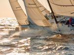 Voiliers filant sur l’eau au coucher du soleil, capturant la vitesse et l’élégance de la navigation.