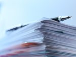 Une pile de documents administratifs illustre le traitement et la gestion de dossiers.